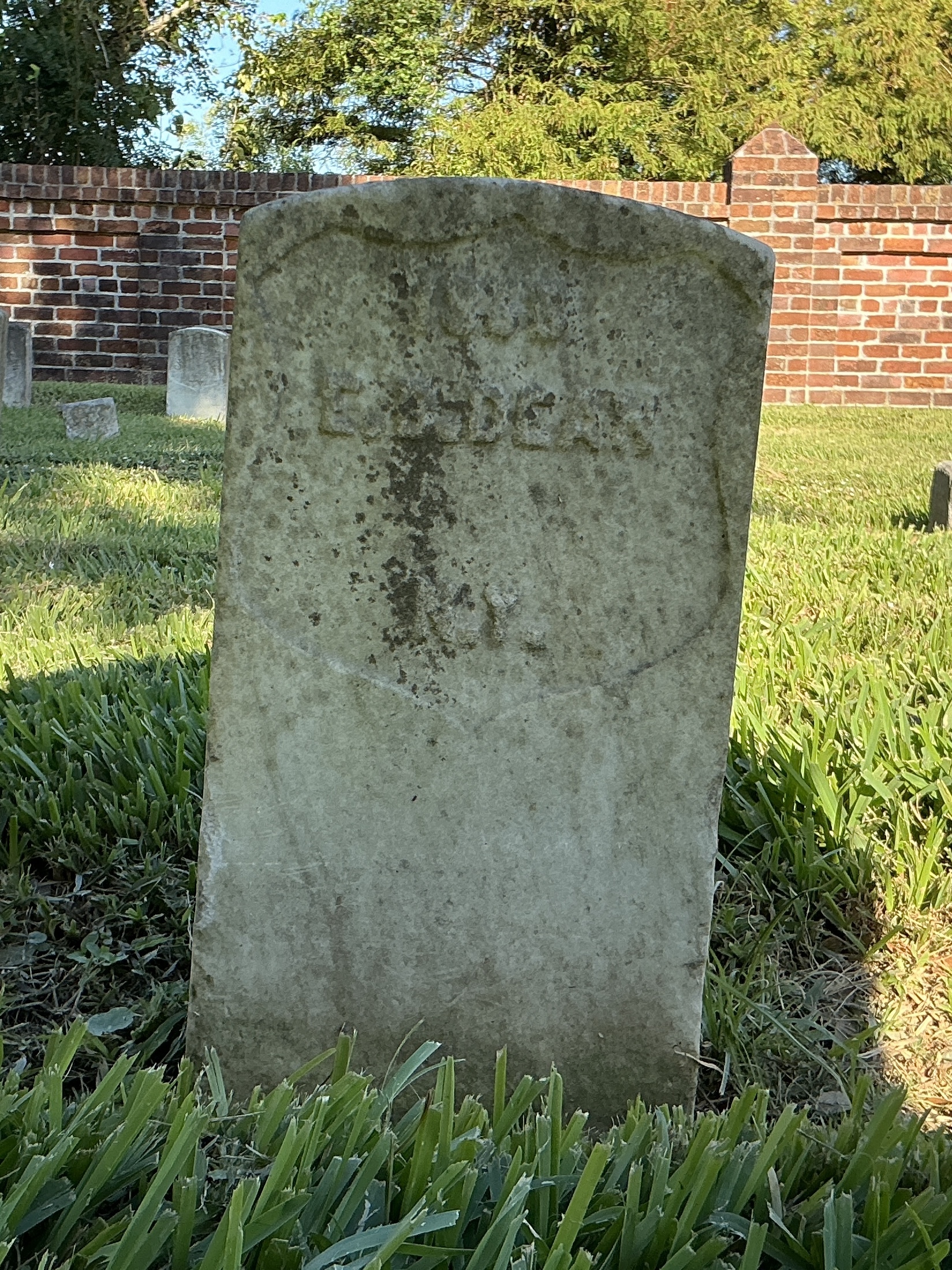 Front of historic upright marble headstone with recessed shield face.