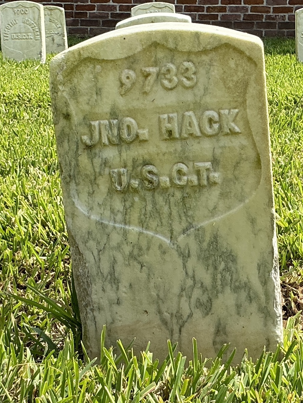 Front of historic upright marble headstone with recessed shield with recessed lettering face.