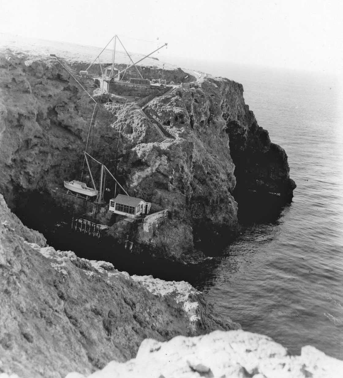 Steep cliff with stairs, buildings, and boat.