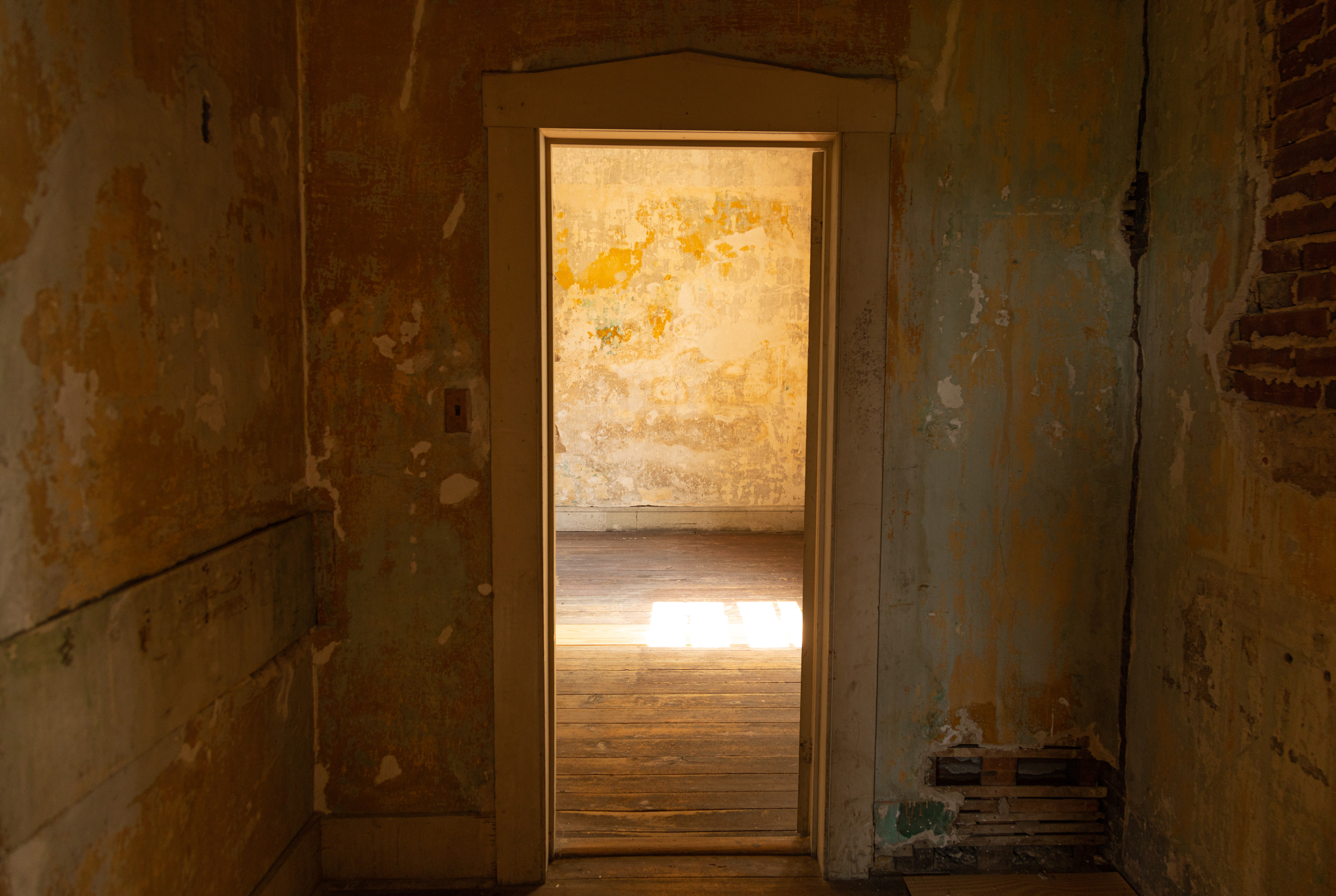 A large door sits in the middle leading from a hallway to a large well lit room. 