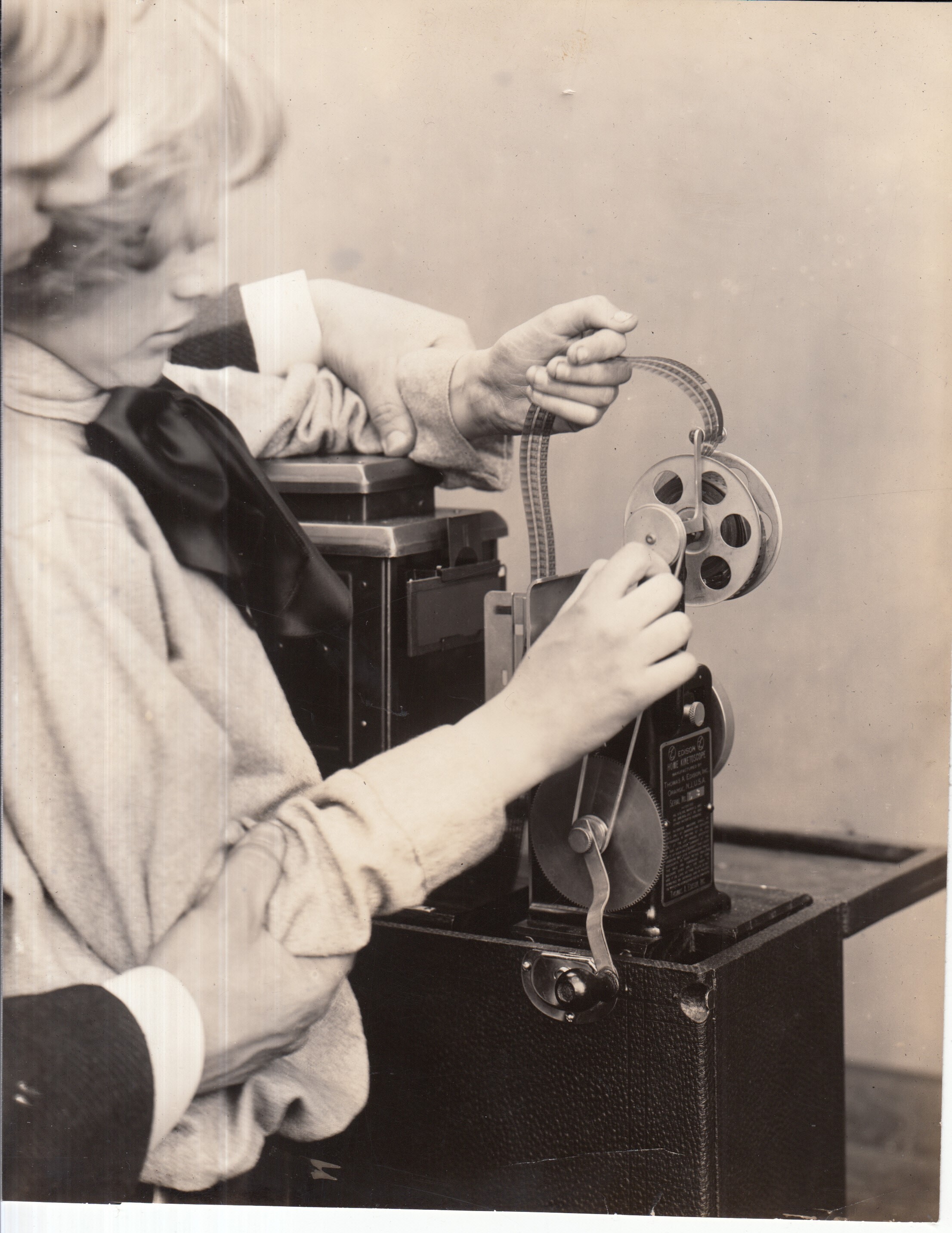 Publicity shot, girl threading film through Edison home projecting kinetoscope.