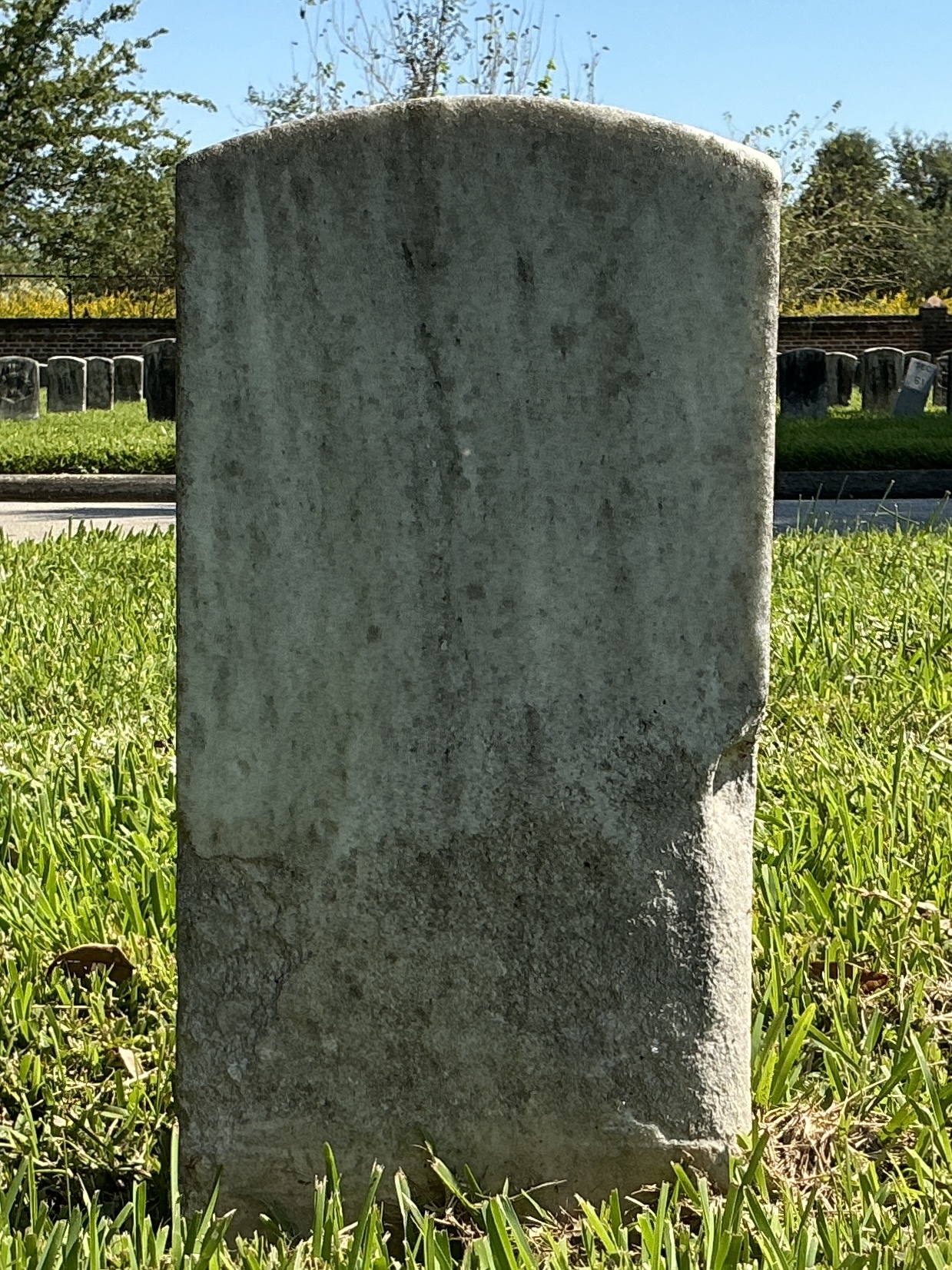 Back of historic upright marble headstone with recessed shield face.