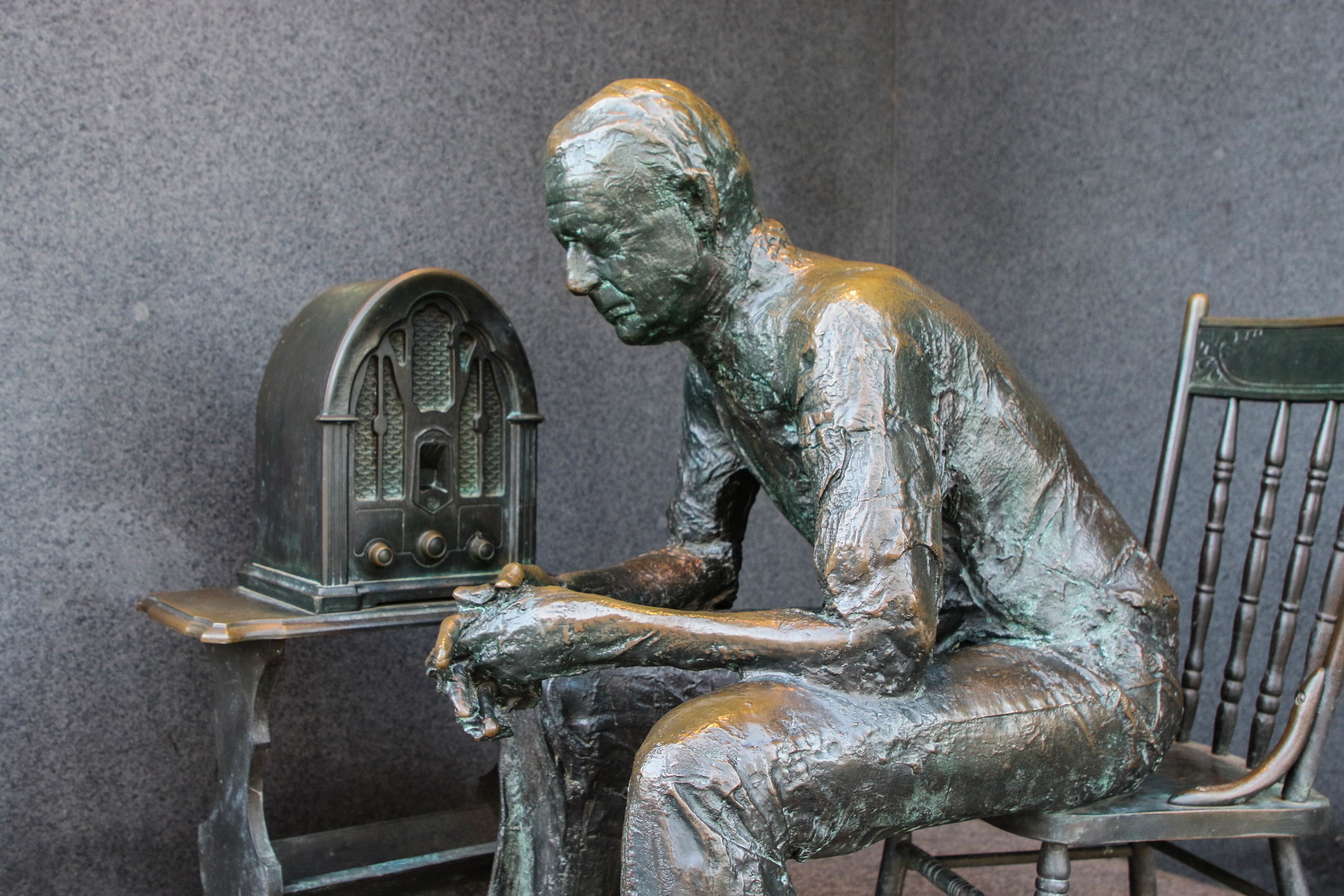 Statue of a man sitting listening to the radio