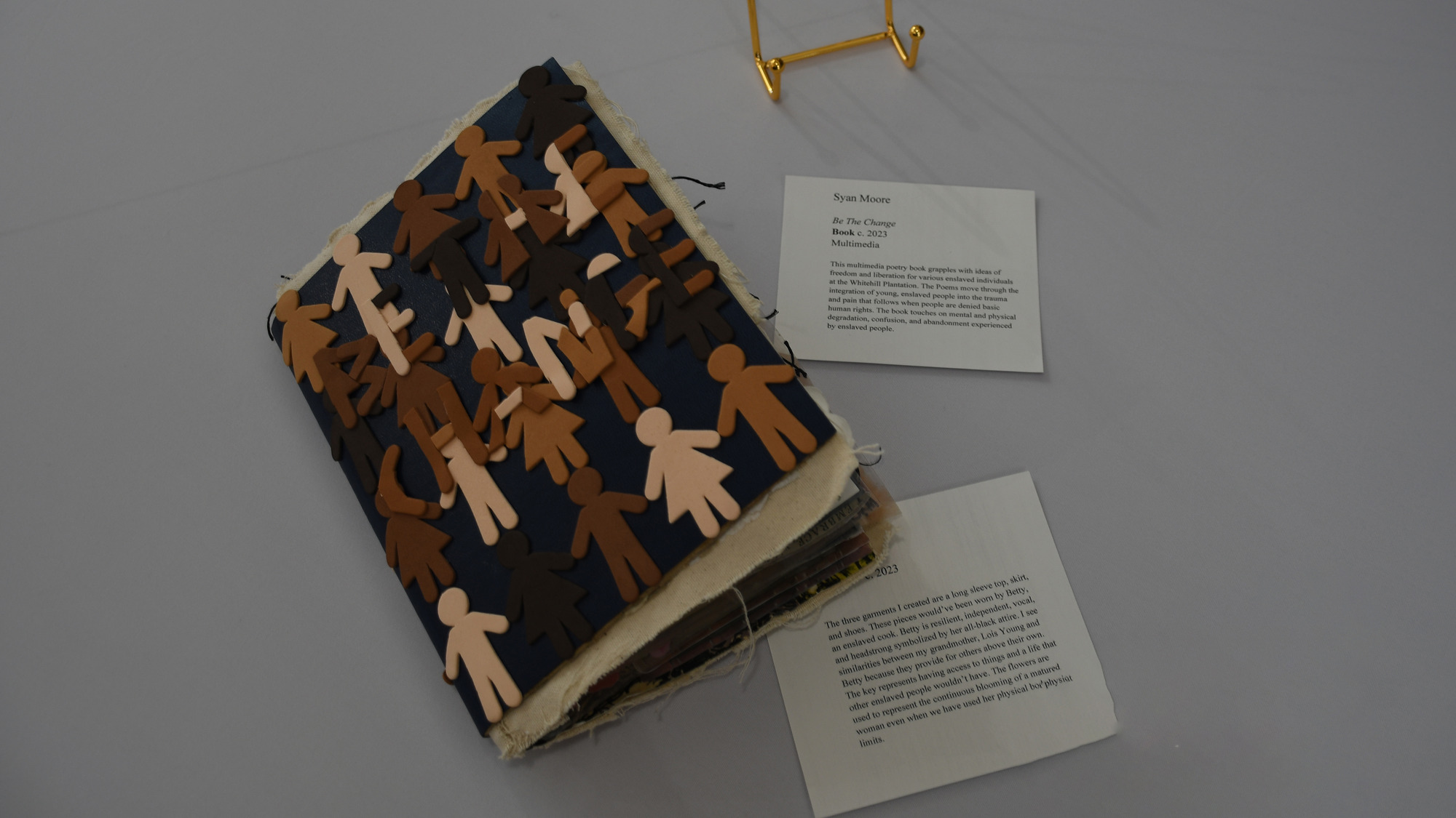 Foam cut into shape of men and women in different shades of cream brown and black overlapping on a closed book cover.