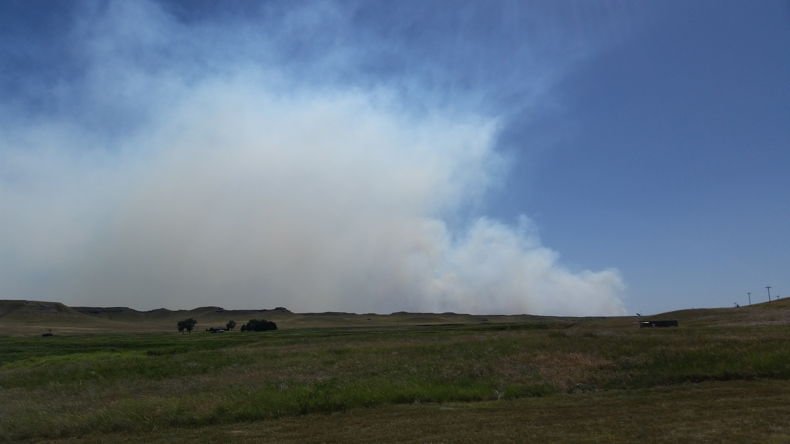 Cloud of white and dark gray smoke over a grassy plain