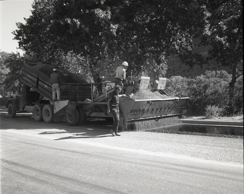 Men operating sealcoating machine while sealcoating parking area in Zion.