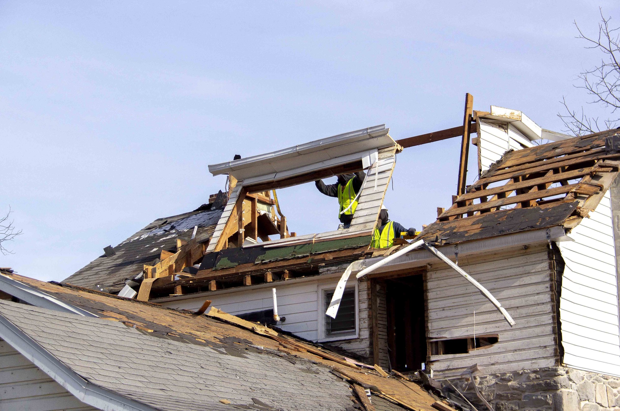 Two hired contractors continue the selective demolition process on the modern third floor additions of the house. The contractors are working to remove the window frame structure that was part of the modern addition.  The roof is gone. 