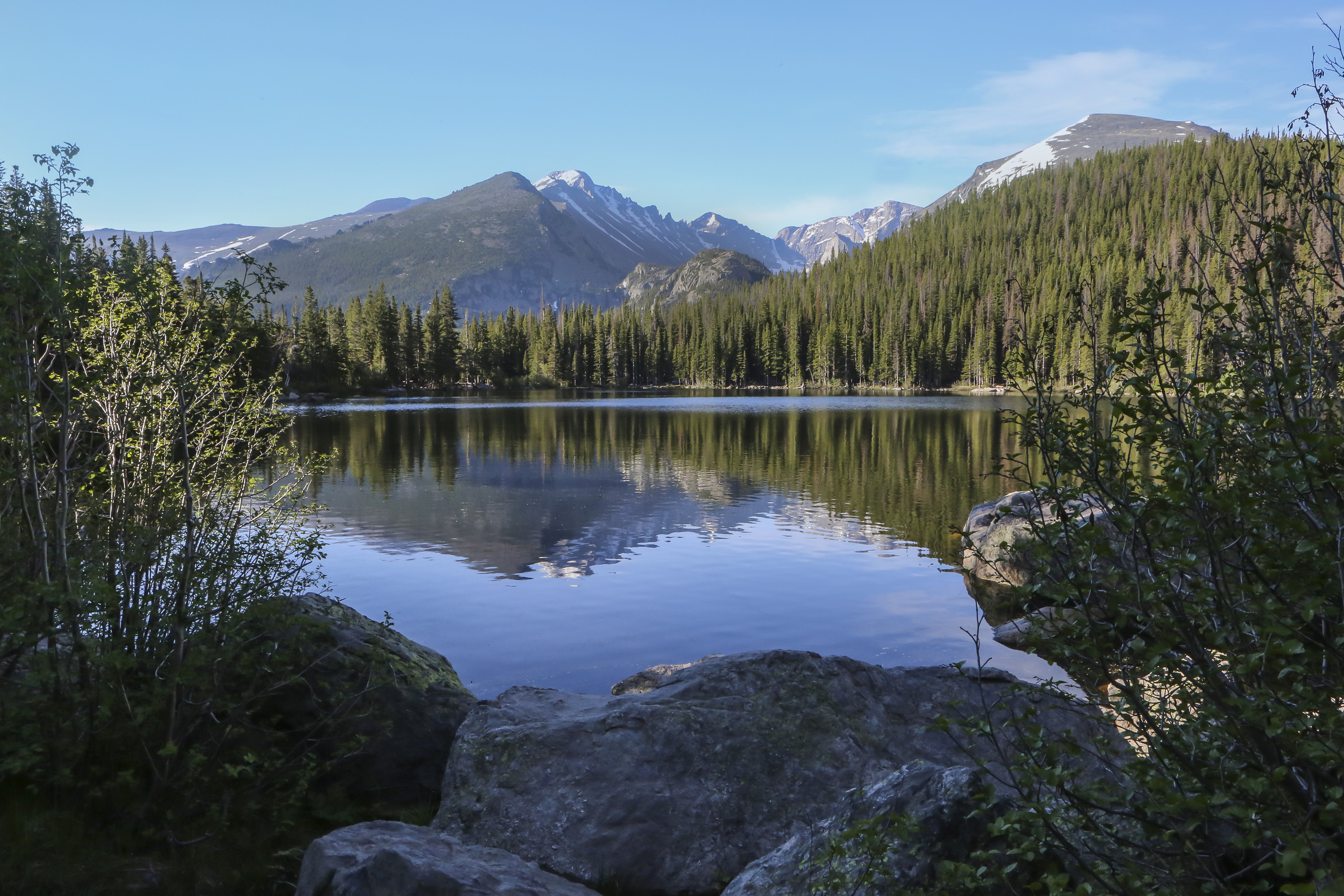 A mountain lake reflects a view of Longs Peak and surrounding peaks.