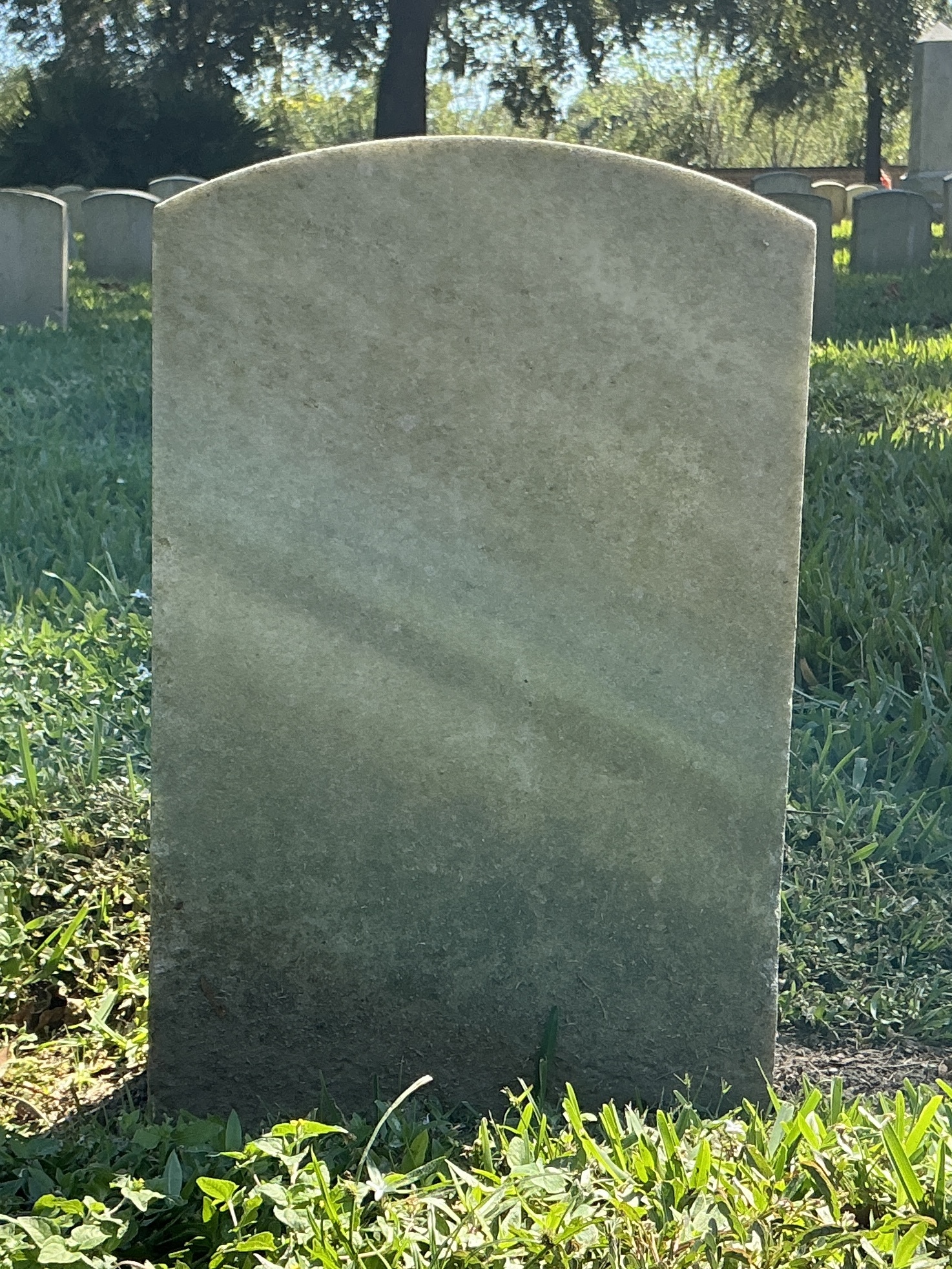 Back of historic upright marble headstone with recessed shield face.
