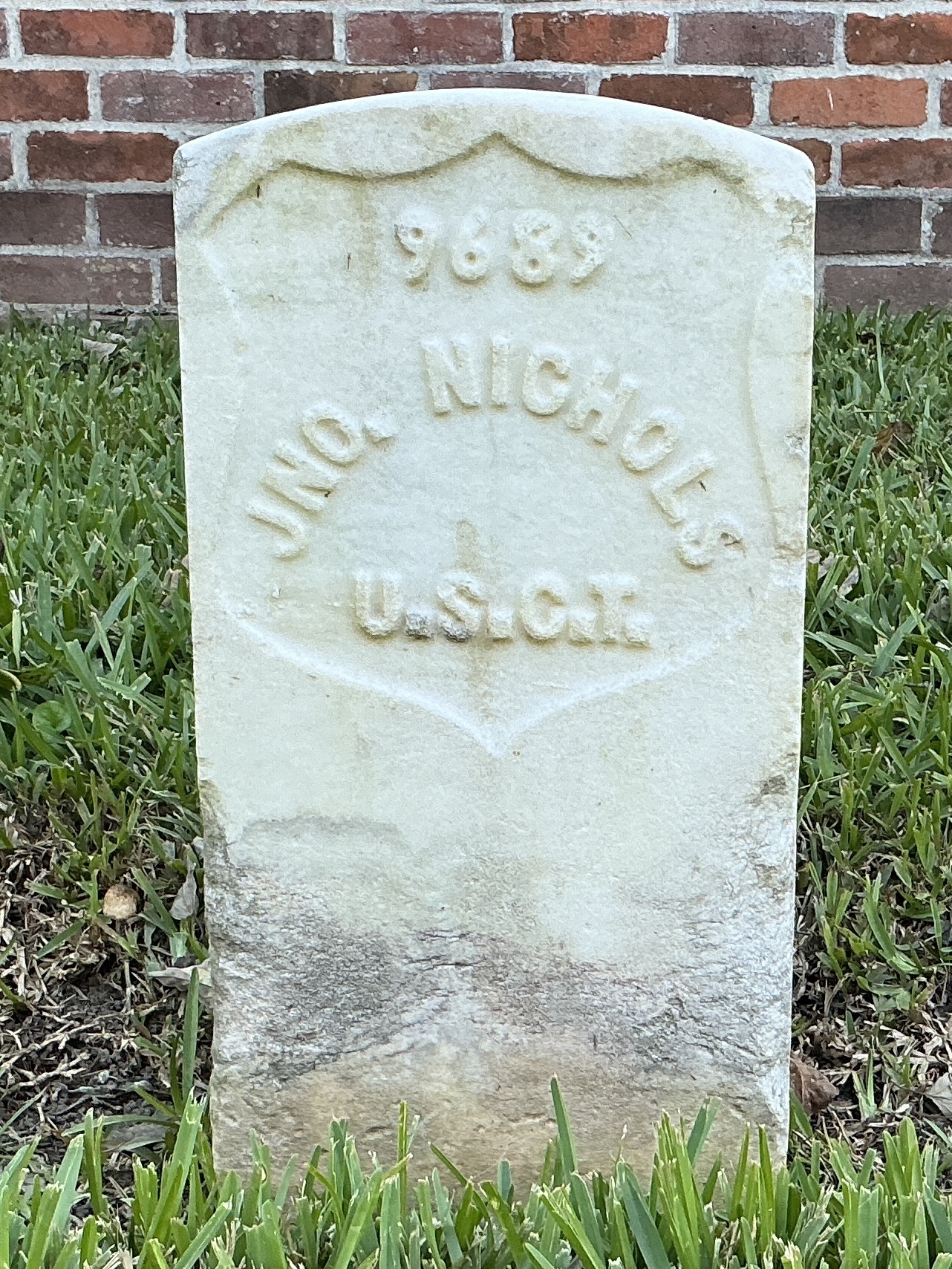 Front of historic upright marble headstone with recessed shield face.
