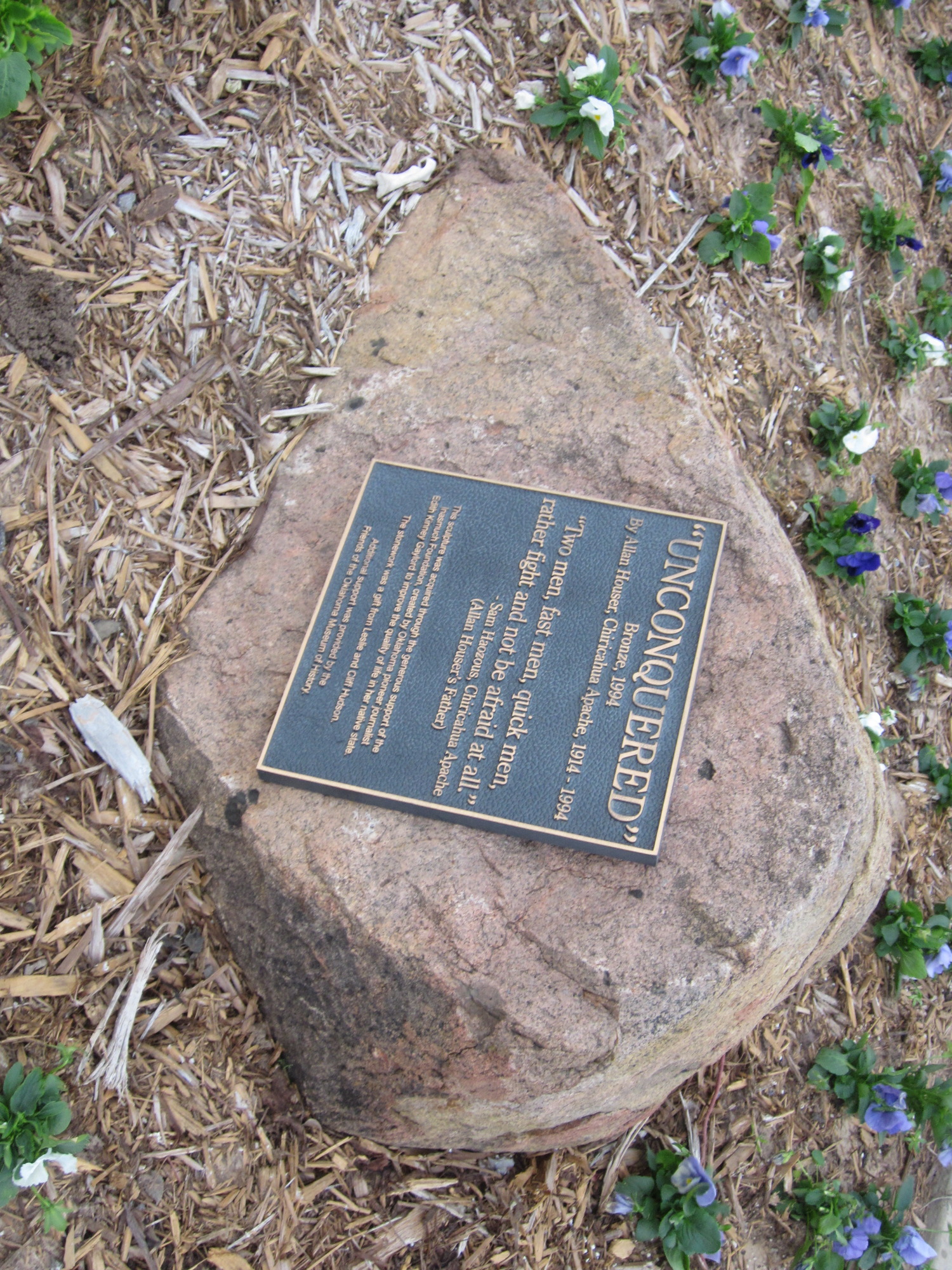 A plaque with some text on a rock.
