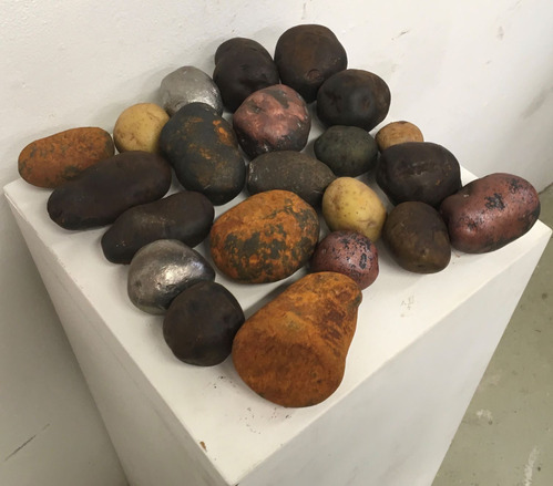 A grouping of cast iron potatoes of different colors: rust, brown, reddish, yellow, silver, black
