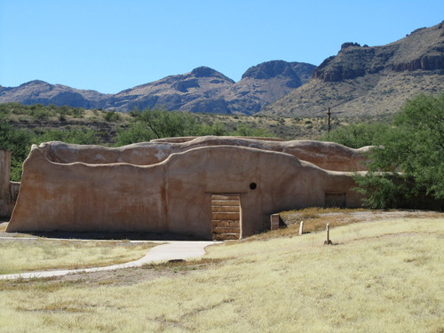 Mission storeroom with mountains behind and low mound in foreground, steps visible through doorway