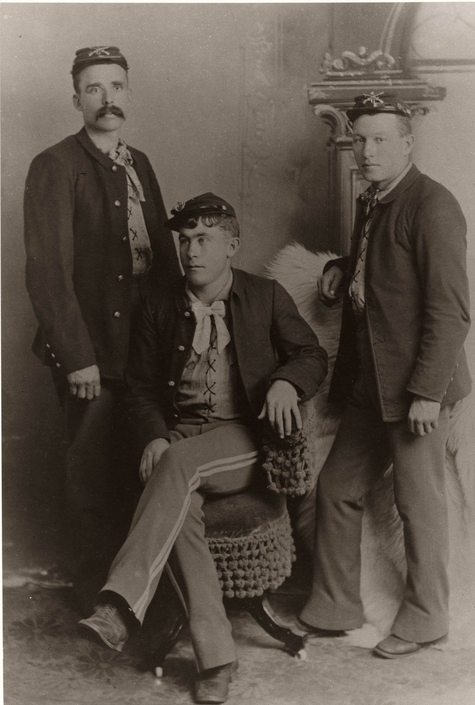Black and white photograph of three men in uniform posing for a portrait in a studio