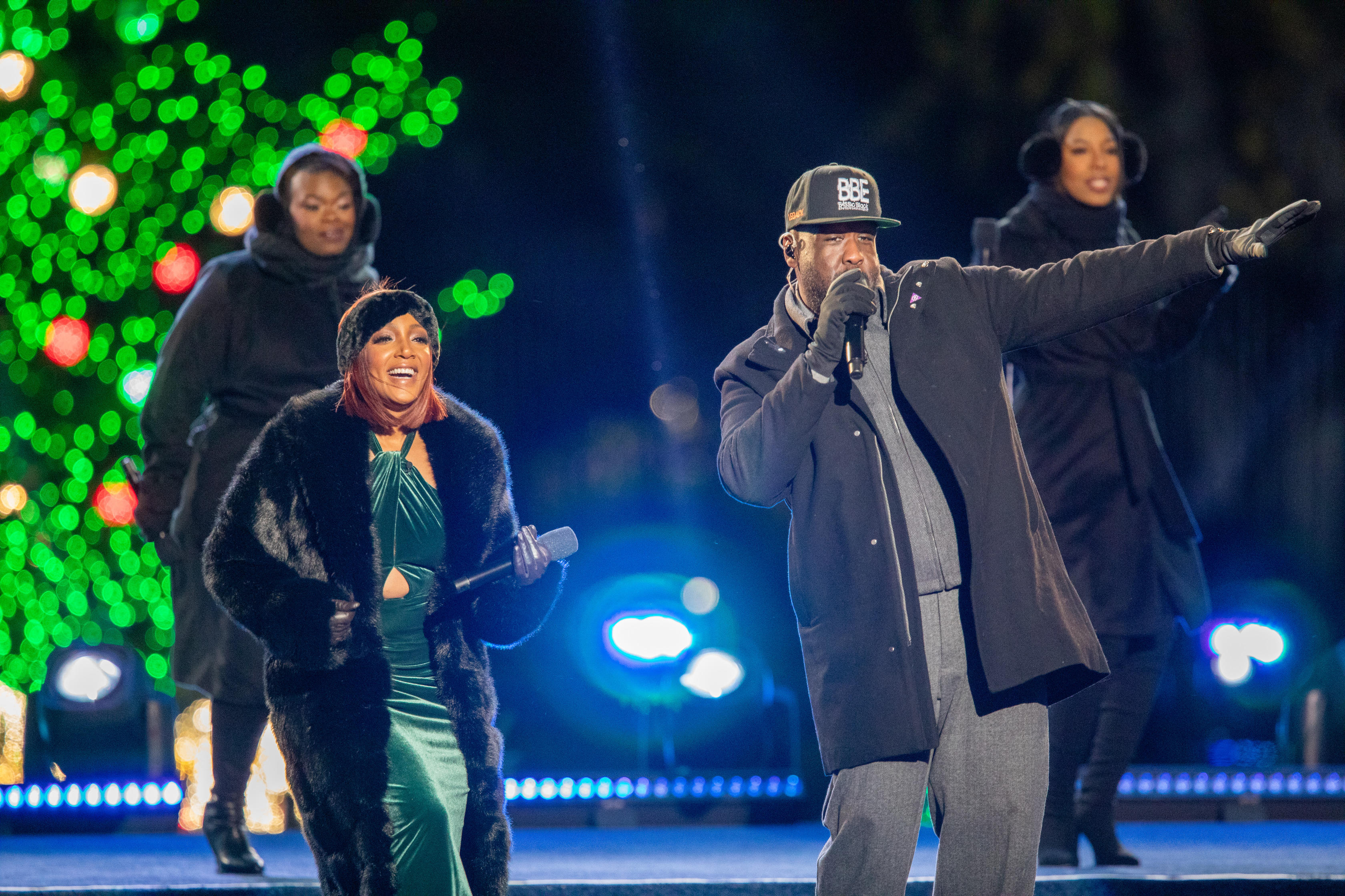 Four performers sing and dance on stage. 