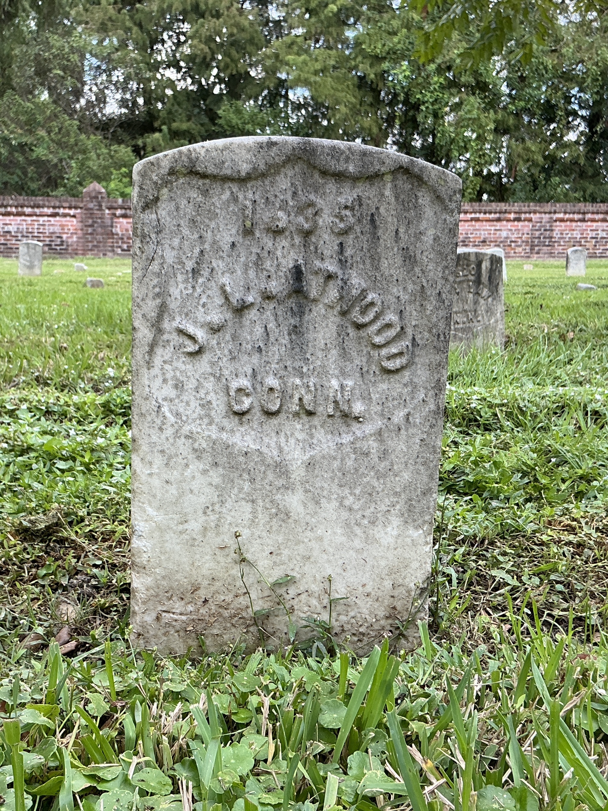 Front of historic upright marble headstone with recessed shield face.