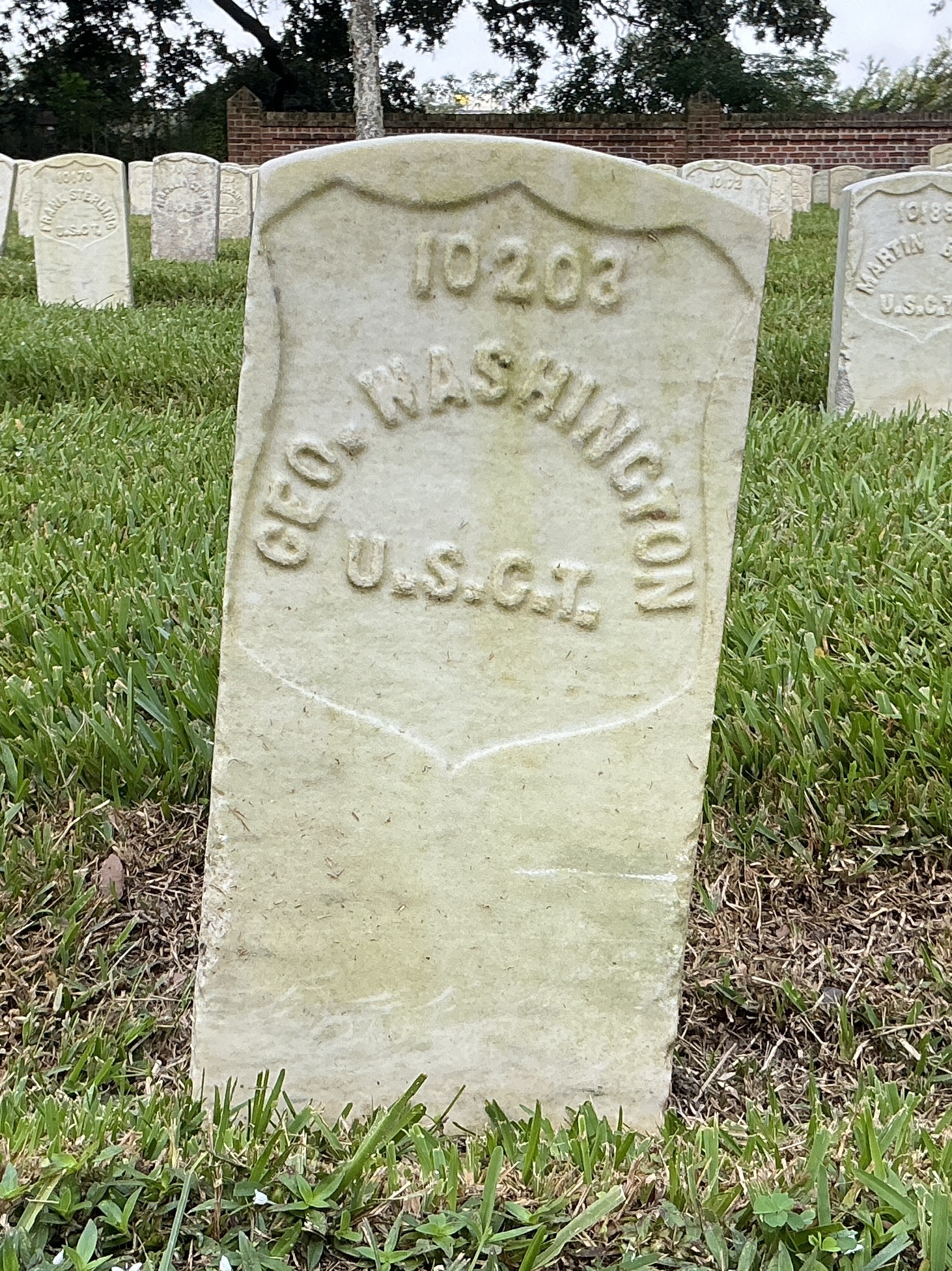Front of historic upright marble headstone with recessed shield face.