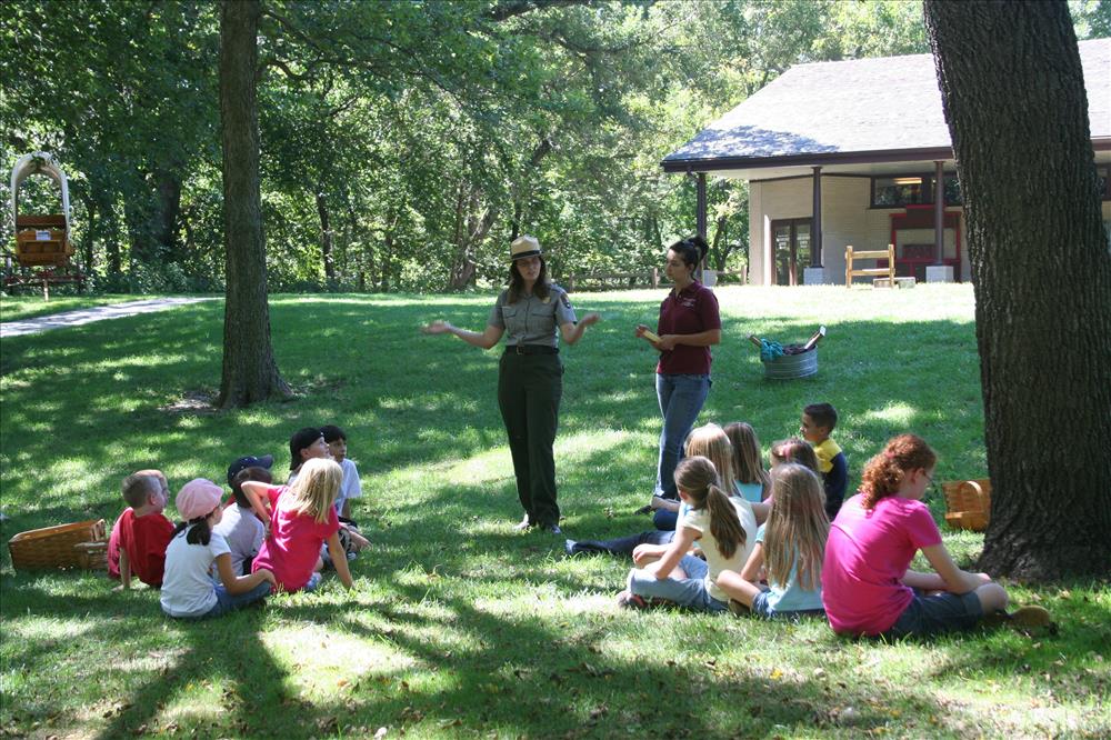 Children sit in two groups while a Ranger explains how to play a game.