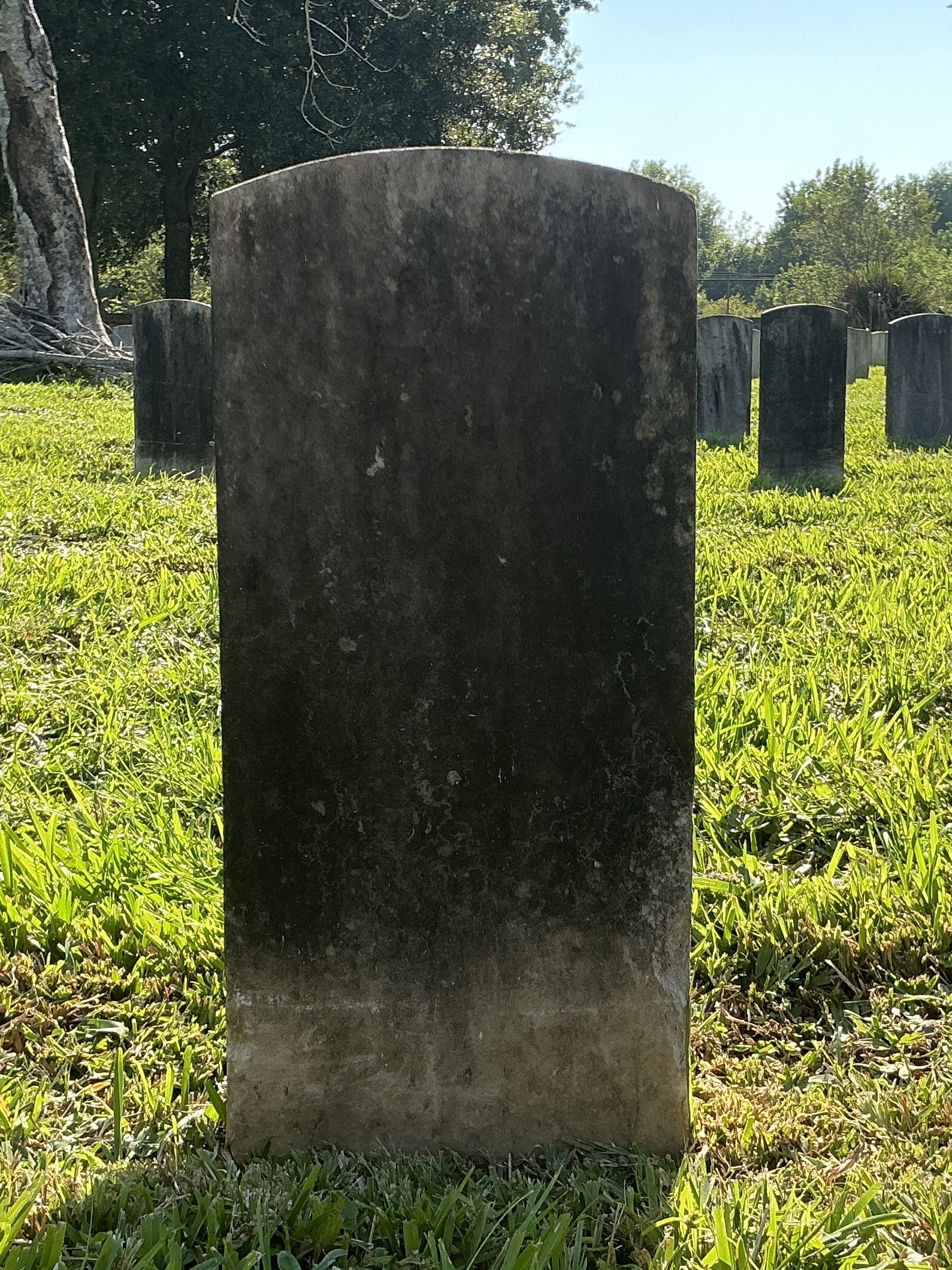 Back of historic upright marble headstone with recessed shield face.