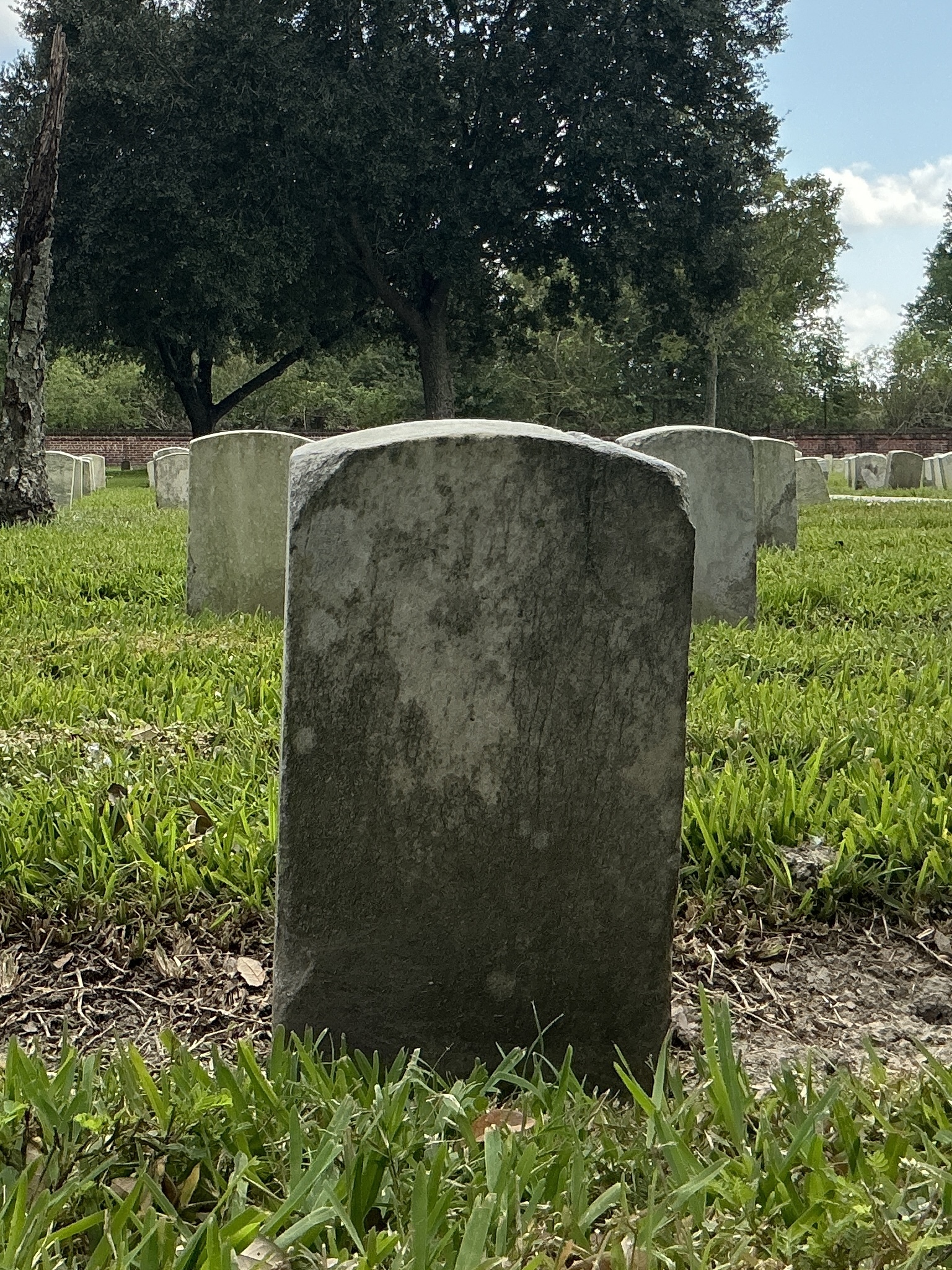 Back of historic upright marble headstone with recessed shield face.