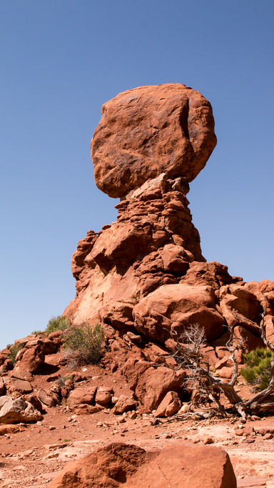A tall, red stone spire stands in the middle of the desert in Arches National Park. 