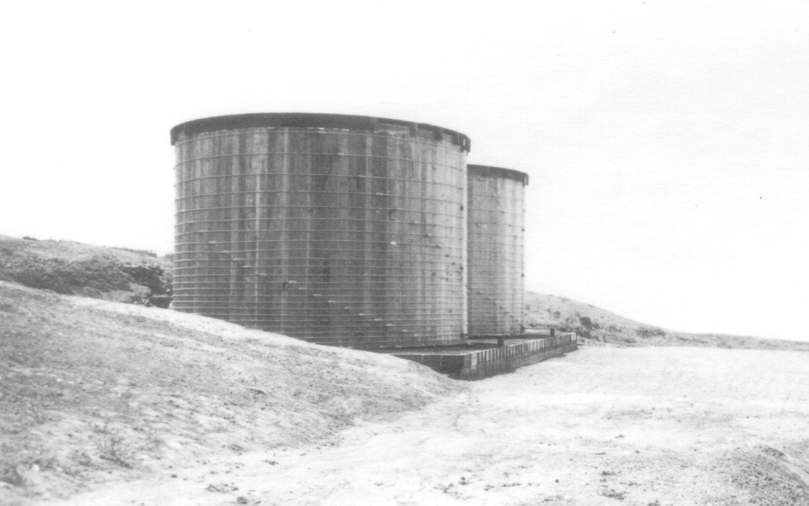Two redwood round water tanks on wood platform.