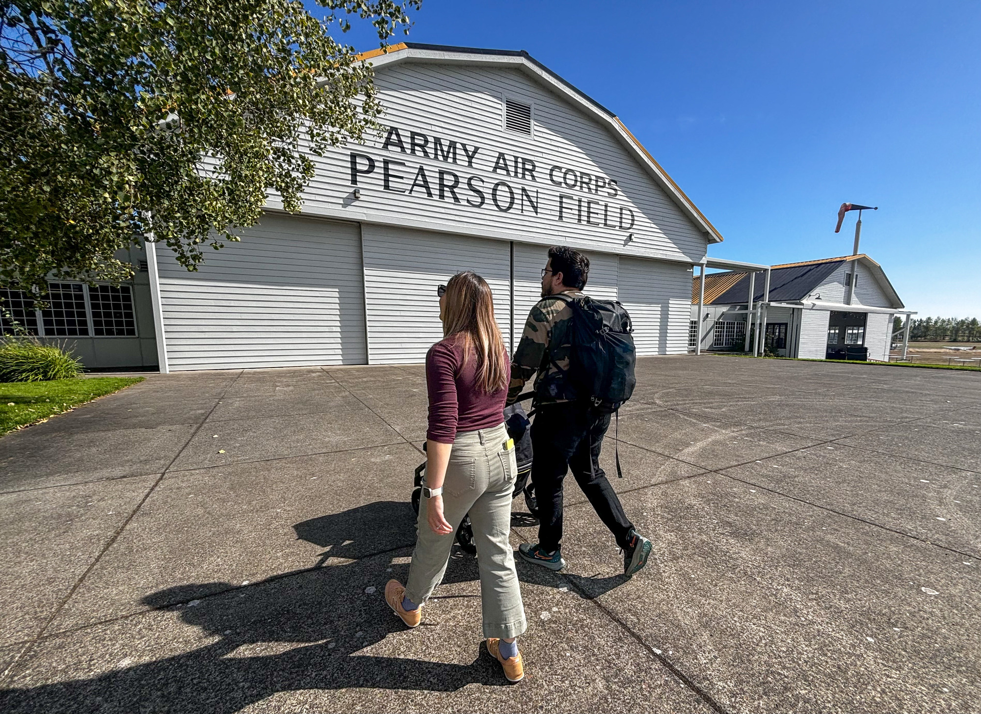 Two adults walk towards a large building with the worlds Army Air Corps Pearson Field. 