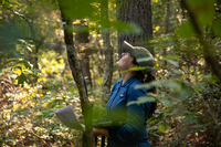 A biologist looks up and smiles. In her hand she holds an iPad and some papers.