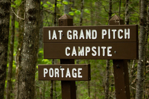A close-up of a sign reading IAT Grand Pitch Campsite Portage.