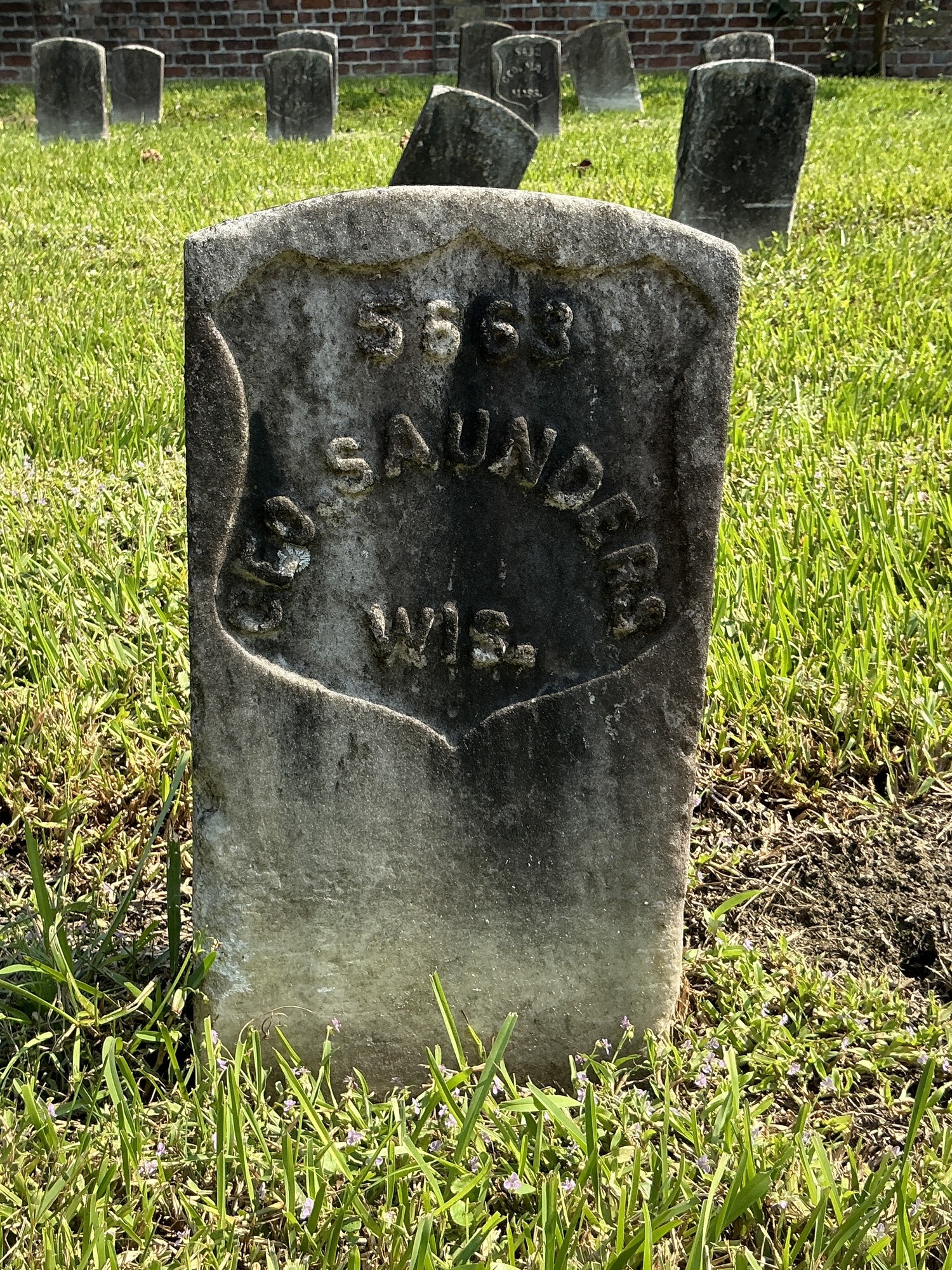 Front of historic upright marble headstone with recessed shield face.