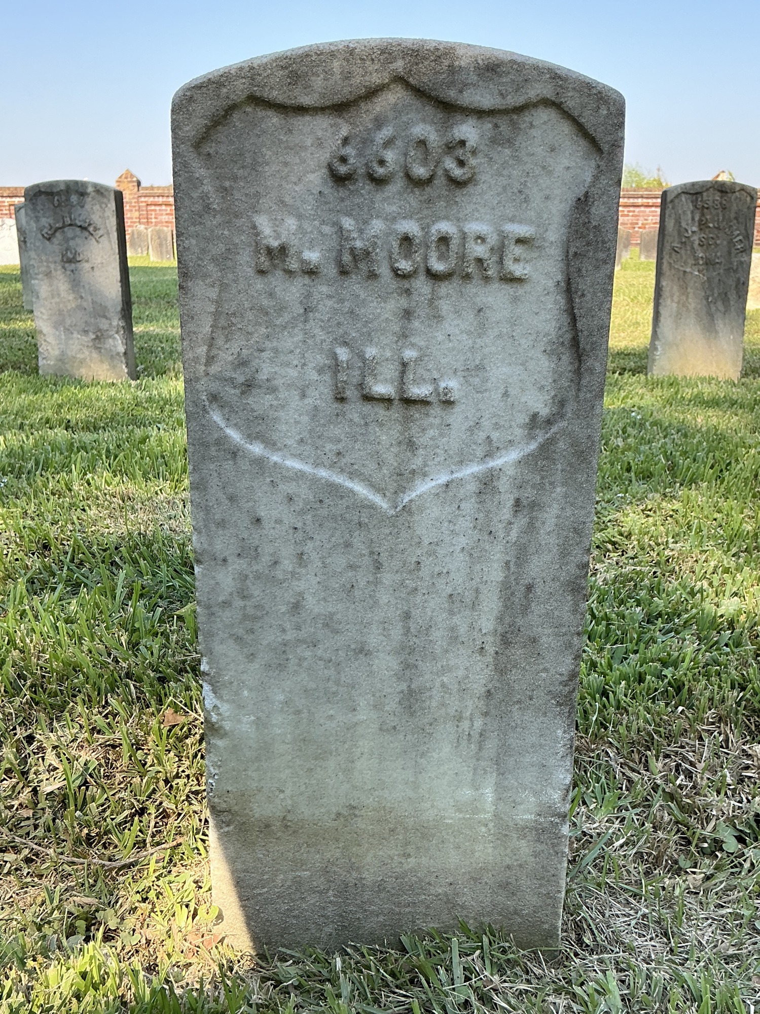 Front of historic upright marble headstone with recessed shield face.