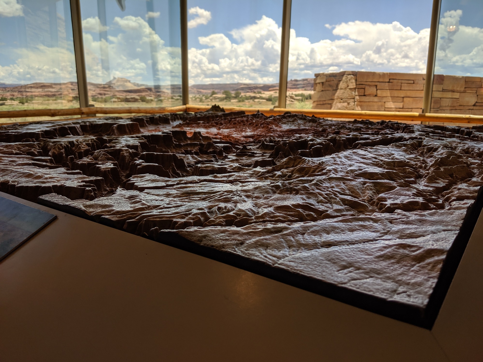 a three-dimensional map showing topographic features with broad windows with rock formations and clouds in the distance