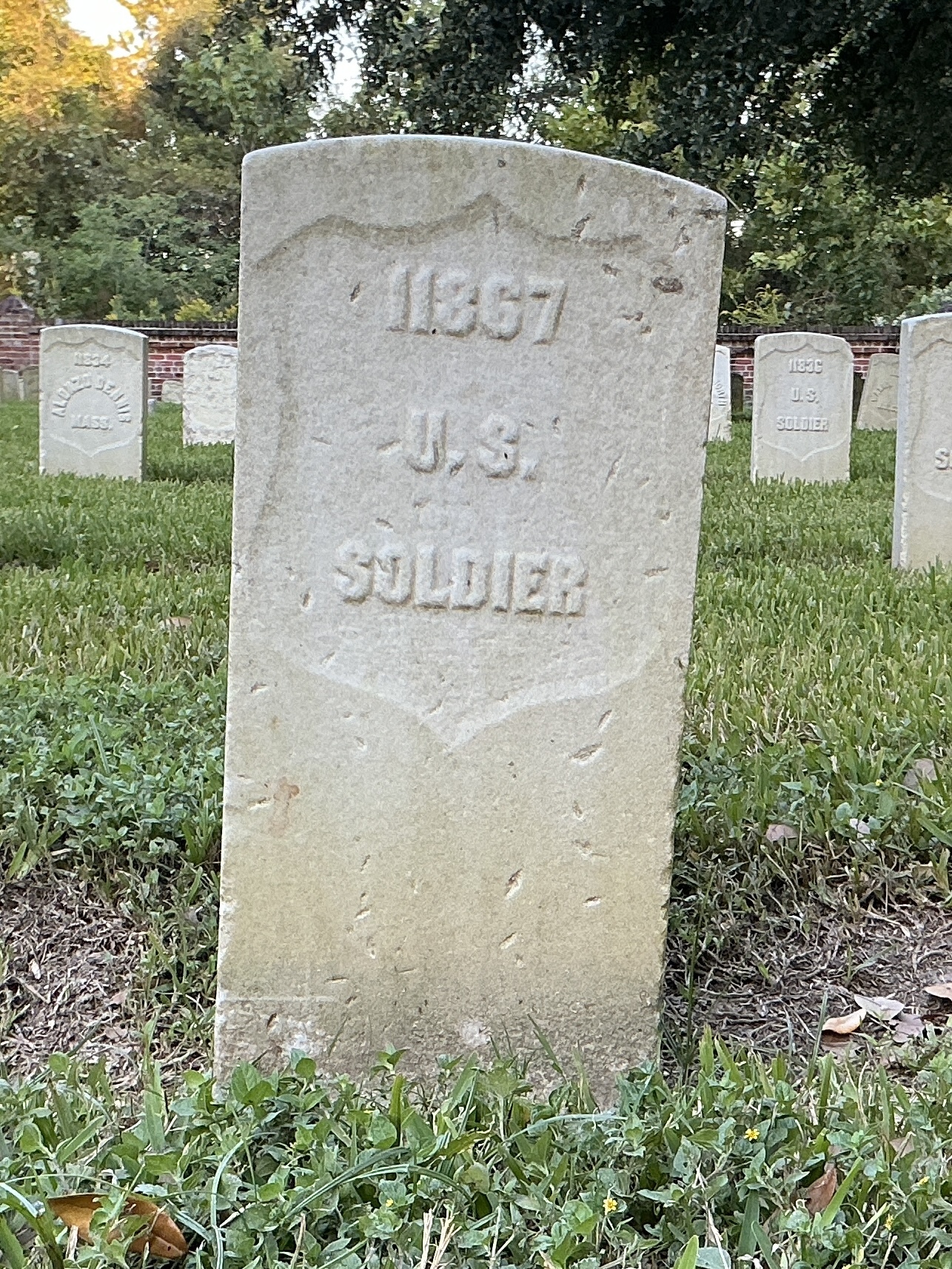 Front of historic upright marble headstone with recessed shield face.