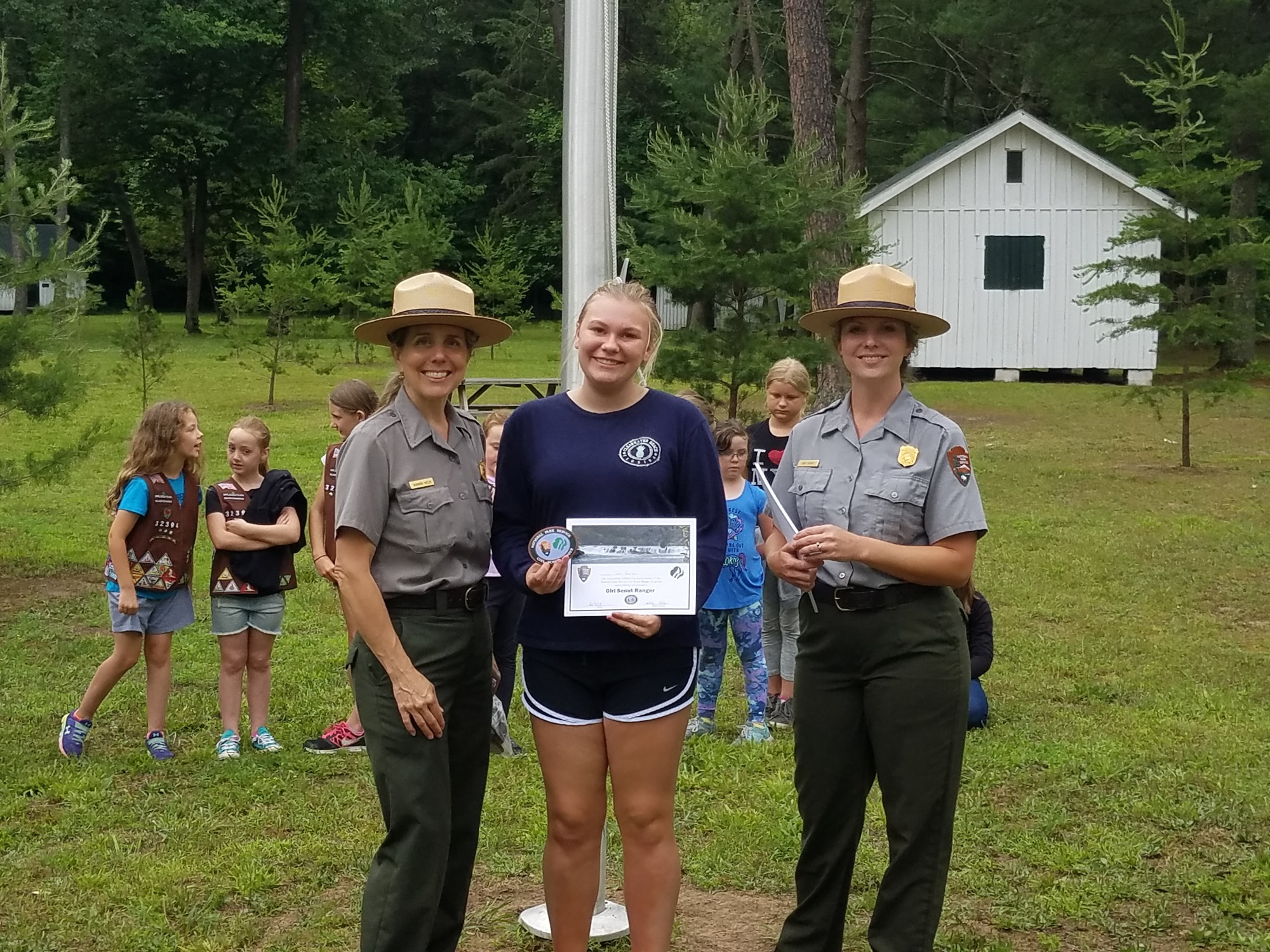 Girl Scout receiving badge with two park rangers