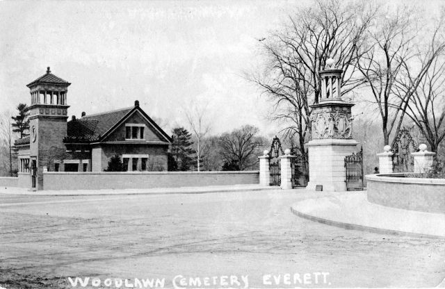 Entrance to a cemetery that includes a building with a tower. 