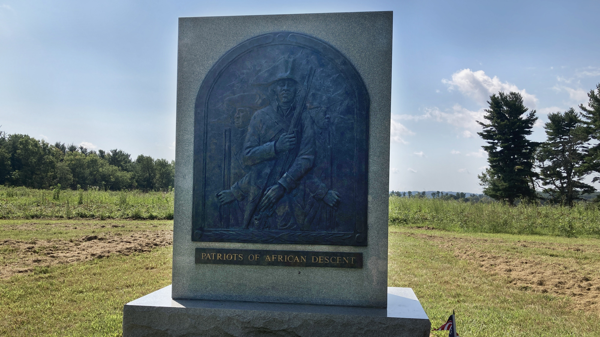 outdoors, stone monument, three african american soldiers stand with muskets, text reads Patriots of African Descent