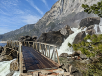 bridge over a water fall. High cliffs visible in background.