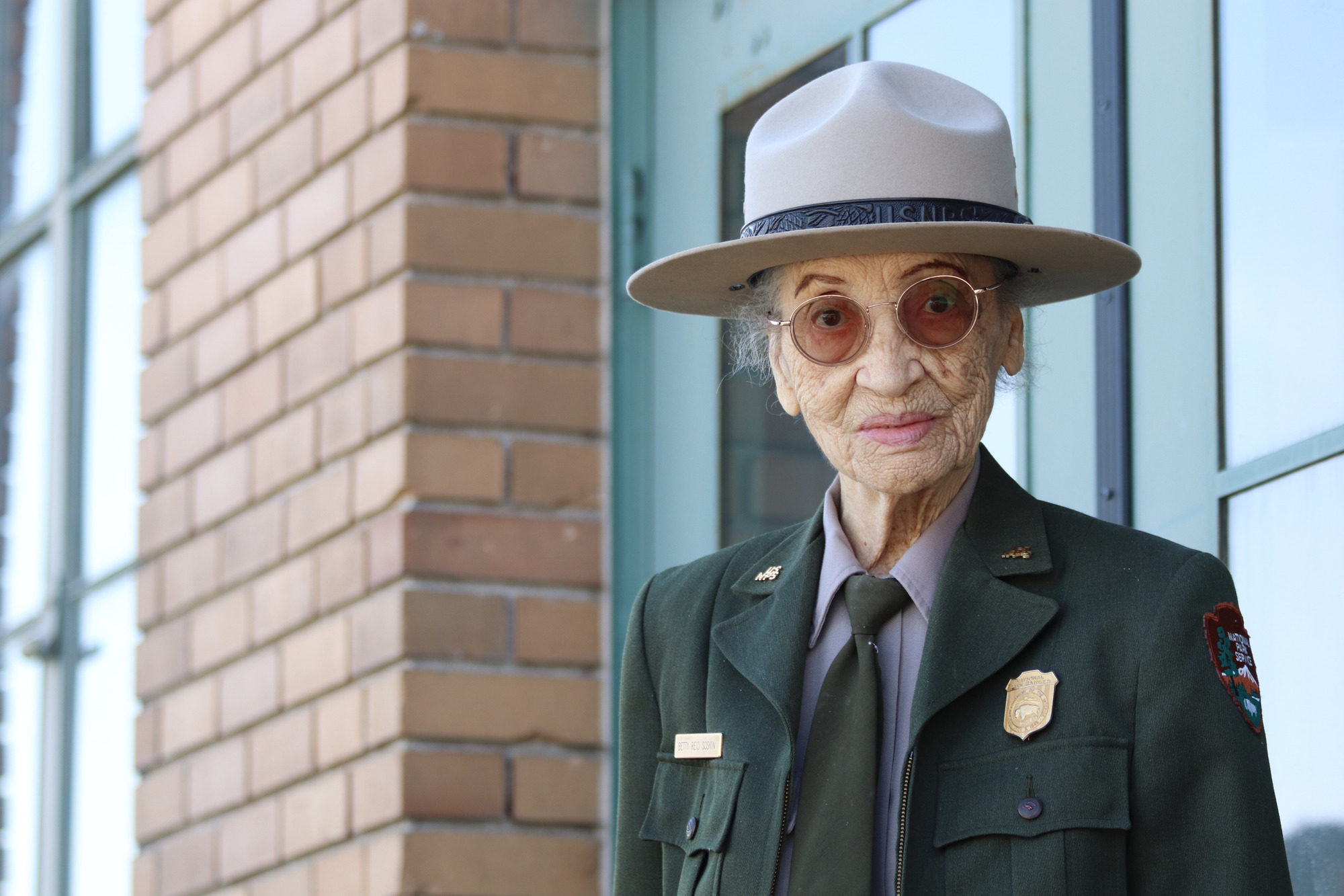 A senior African American woman in a ranger uniform smiles at the camera. 