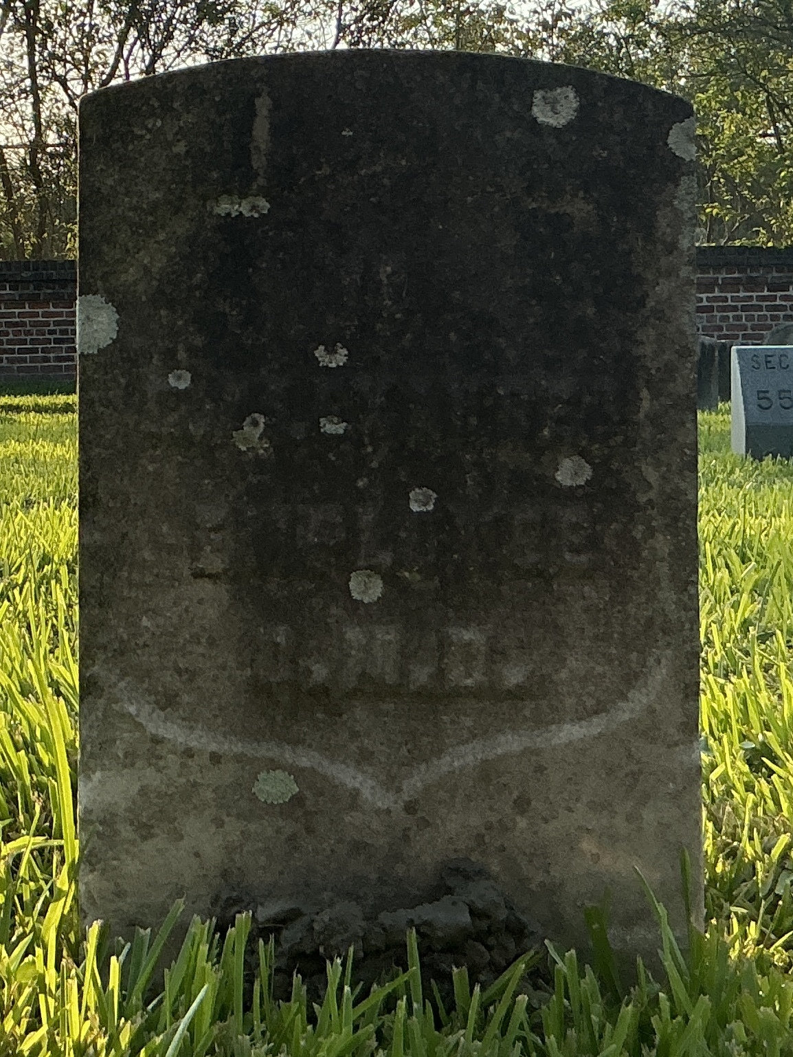 Front of historic upright marble headstone with recessed shield face.