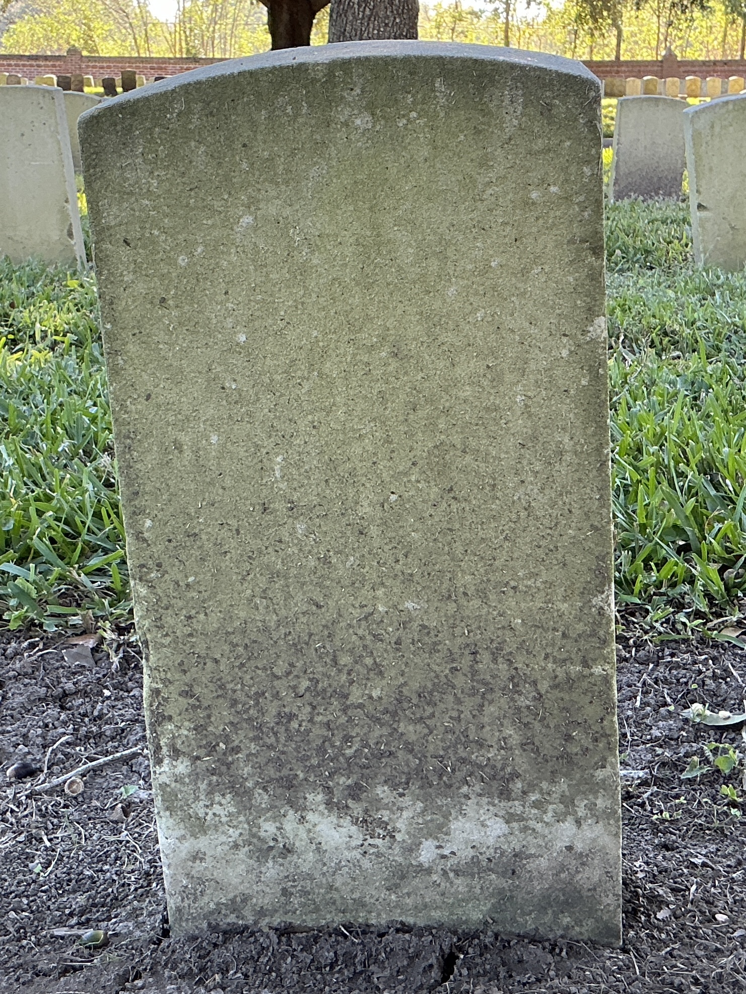 Back of historic upright marble headstone with recessed shield face.