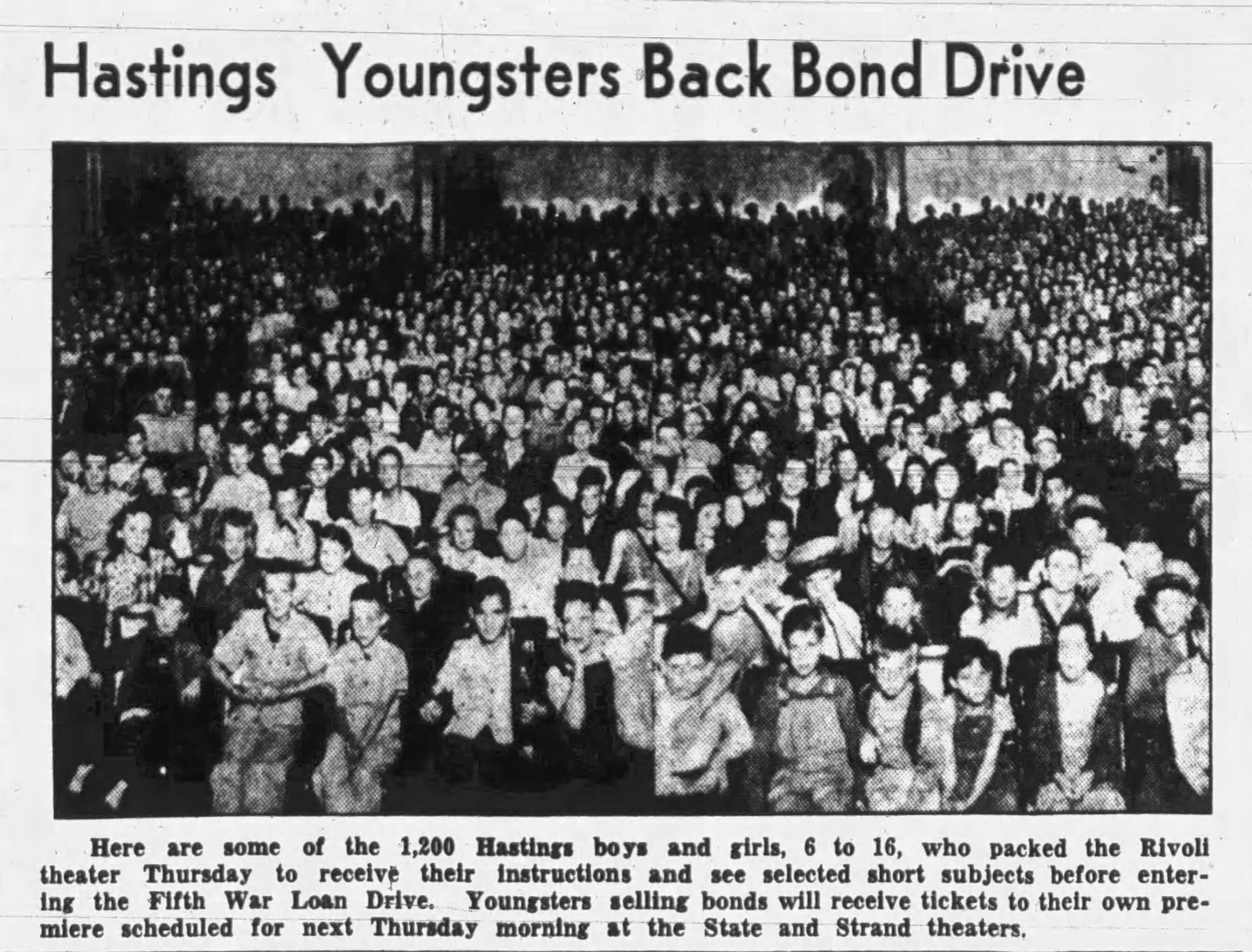 Black and white photo of hundreds of children sitting close together in a large room