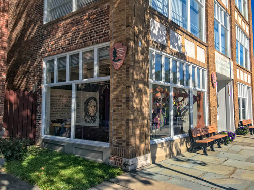 Three-story brick building with an NPS arrowhead logo handing on the outside and museum exhibits through the window
