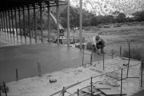 Workers leveling cement in corner during construction of headquarters addition.
