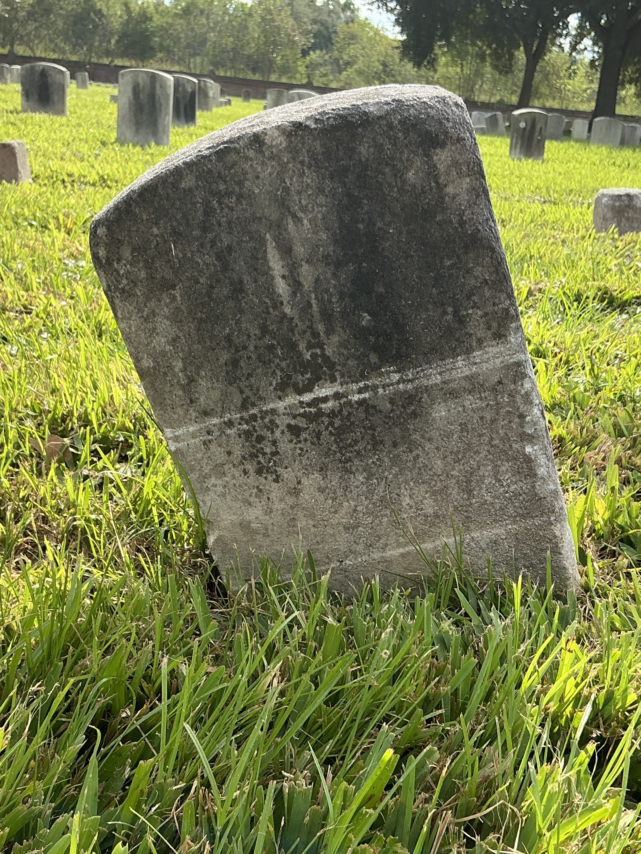 Back of historic upright marble headstone with recessed shield face.