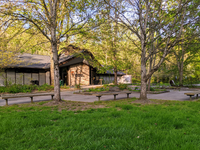 A building with sidewalks, benches, grass, and trees in front of it.