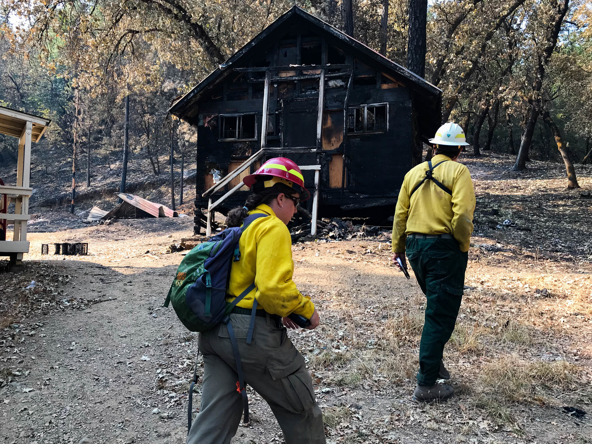 A hydrologist and geologist walking past a burnt cabin