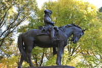 A Major General with a cocked hat sits on a horse, whose four hooves touch the based. The horse's mouth is open and his tail is slightly tucked. Trees are in the background