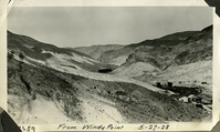 This is an historic black and white photograph from the Scotty's Castle Historic Photograph Collection, Death Valley National Park of Upper Grapevine Ranch from Windy Point looking east up Grapevine Canyon, Scotty's Castle Stables under construction. May 27, 1928. Photographed by Mat Roy Thompson. Grapevine Canyon Spring in center. Indian Camp at right above Stable.