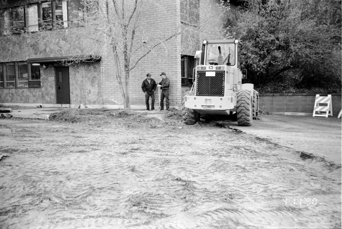 Workers discussing the construction of the headquarters addition while standing next to a construction vehicle.