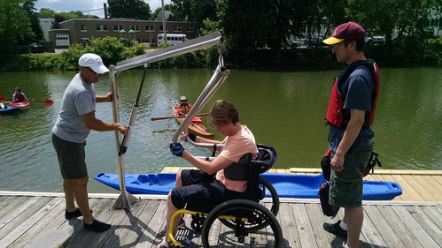 A women is lowered into a kayak for adaptive paddling on the Erie Canal at Fairport, NY